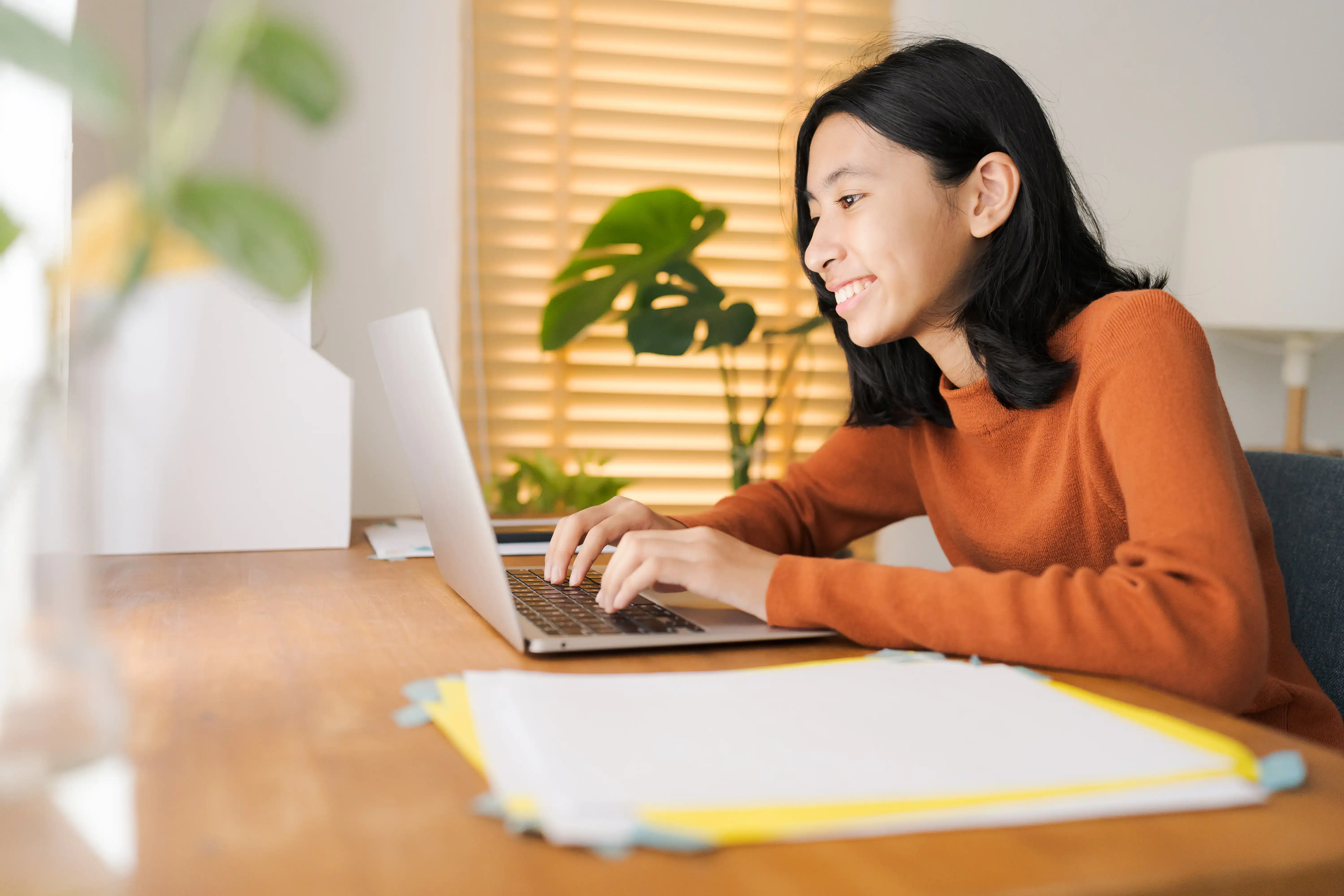 Young girl in orange shirt studying online - K-12 virtual tutoring